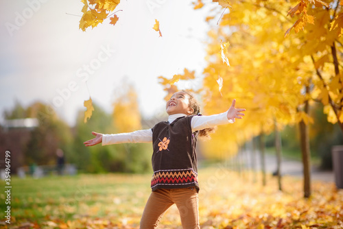 adorable little girl with autumn leaves in the beauty park.