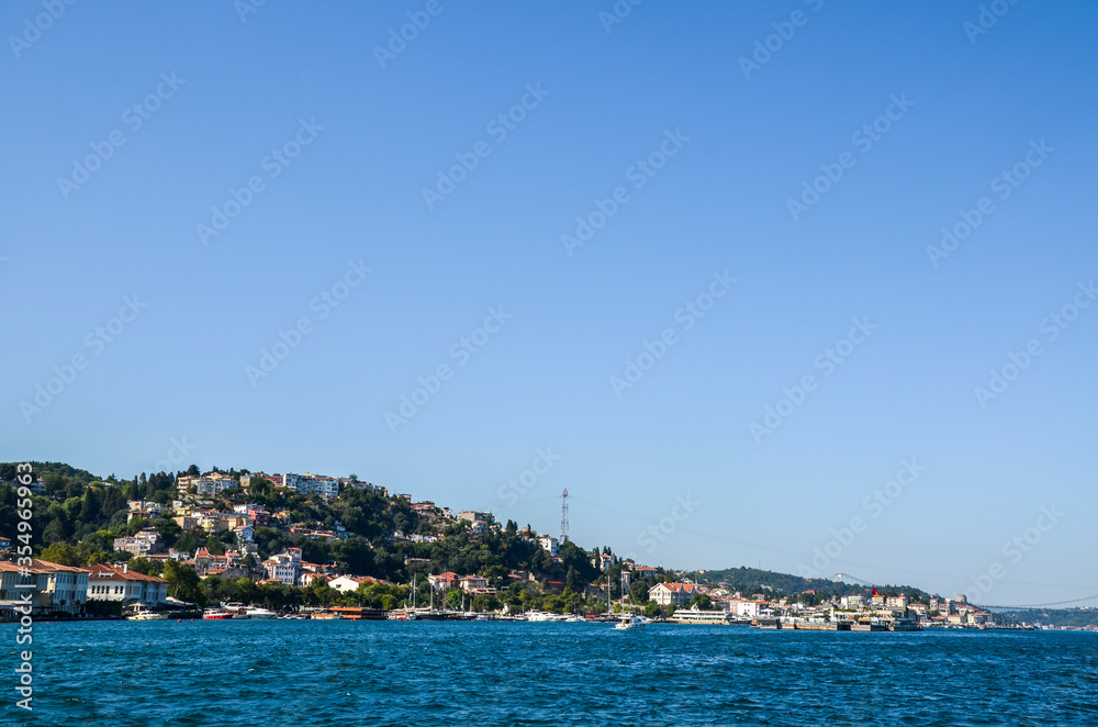 Houses on the coast of the Bosphorus strait. Beautiful view of coastline in Istanbul with luxury residential buildings and cater boats