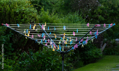 Foto Multi-coloured plastic pegs on a rotary clothes line in an urban garden