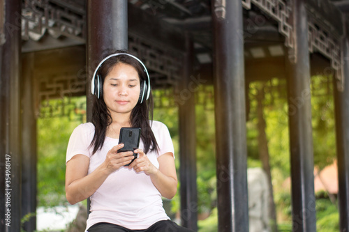 pretty girl listen to music with wireless earphone in garden to relax