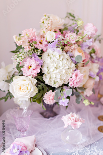 Wedding table decor. Beautiful bouquet with roses and peonies. Lace tablecloth and candles in candlesticks