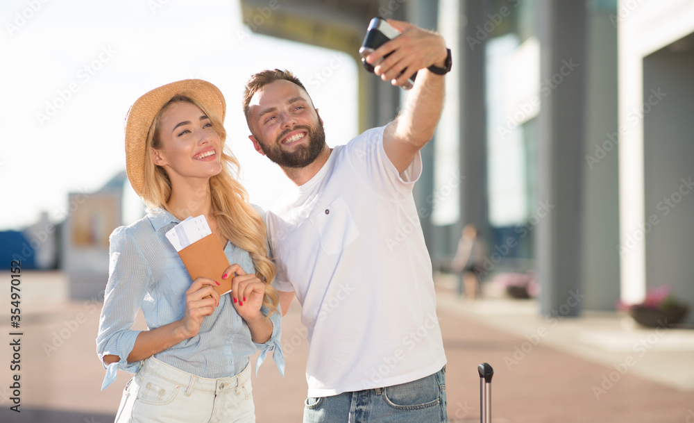 Happy couple taking selfie near airport, waiting for boarding