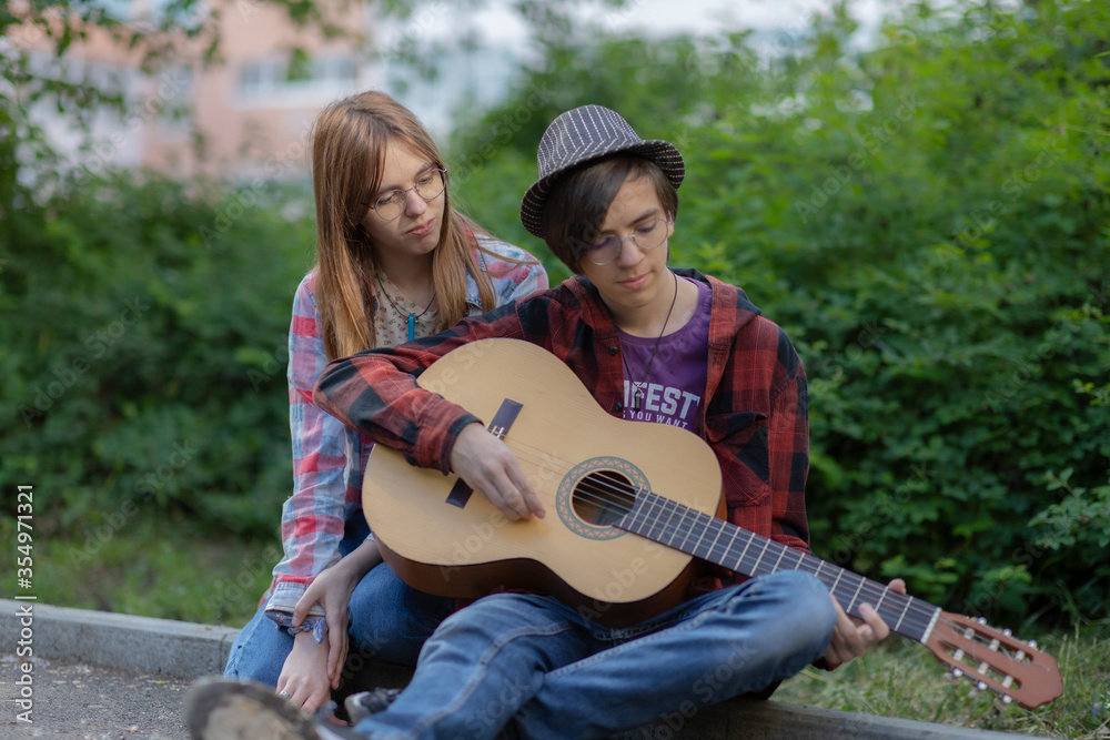 a pair of hipie boy and teen girl play guitar sitting on the sidewalk Asking For Money Donation a pair of hipie boy and teen girl play guitar sitting on the sidewalk Asking For Money Donation