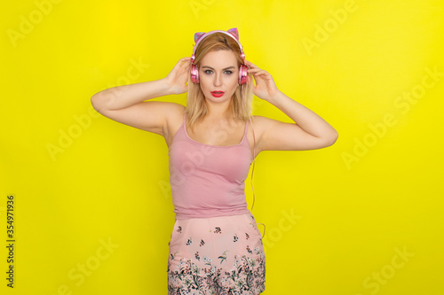 Blonde woman in summer clothing wearing pink headphones © yevgeniya131988