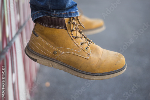 Closeup of man sitting in a little wall in the street wearing mountain boots