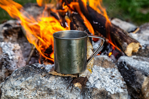steel cup on an open fire in nature. Cooking on fire. Camping in summer.