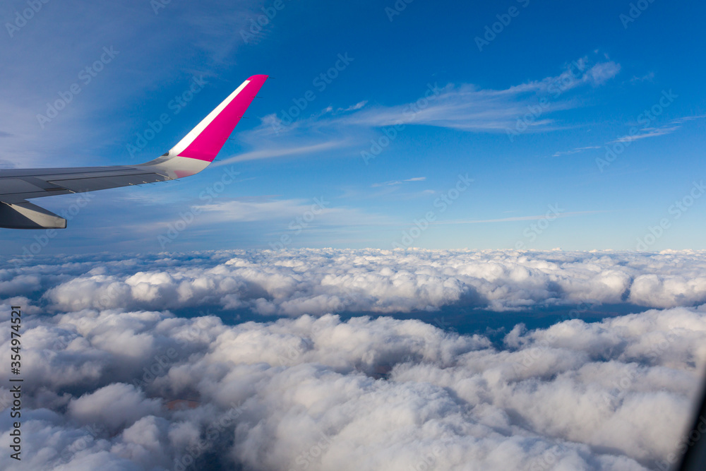White clouds and airplane wing behind the porthole White clouds and airplane wing behind the porthole
