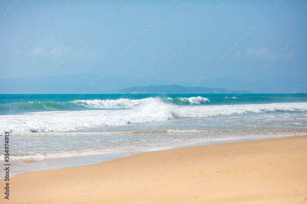 Summer beautiful seascape with foamy waves covered sandy beach on tropical island. Natural beauty of exotic resort. Concept of travelling and relax.