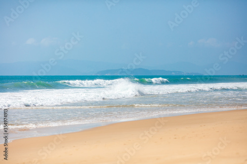 Fototapeta Naklejka Na Ścianę i Meble -  Summer beautiful seascape with foamy waves covered sandy beach on tropical island. Natural beauty of exotic resort. Concept of travelling and relax.