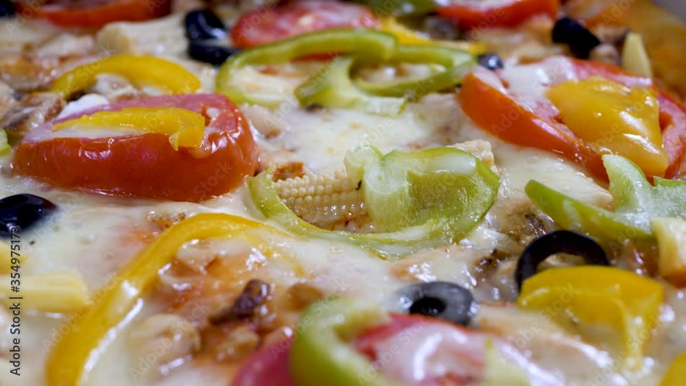 Pizza with vegetables in cardboard box. Pieces of chicken meat, melted hot cheese, sliced tomato pieces, black olives, yellow capsicum or sweet pepper, cobs of young corn. Pizza delivery or menu