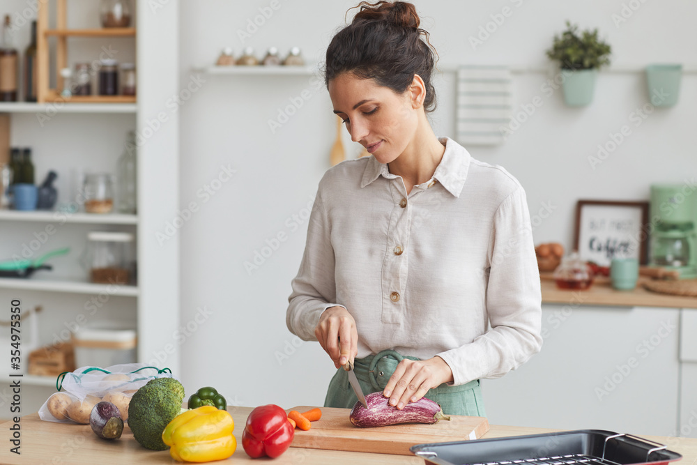 Young woman cutting fresh vegetables on cutting board she preparing dinner in the kitchen