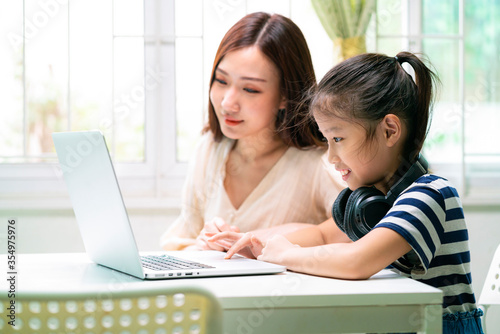 Asian girl and her mother using laptop for online study during homeschooling at home. homeschooling, online study, new normal, online learning, corona virus or education technology concept © tuastockphoto