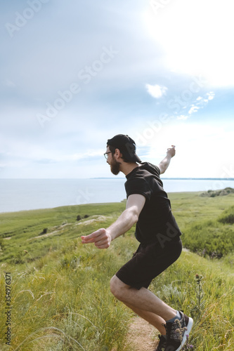 Happy man is dancing on a hill near the sea on nature. Enjoy life, outdoor activities.