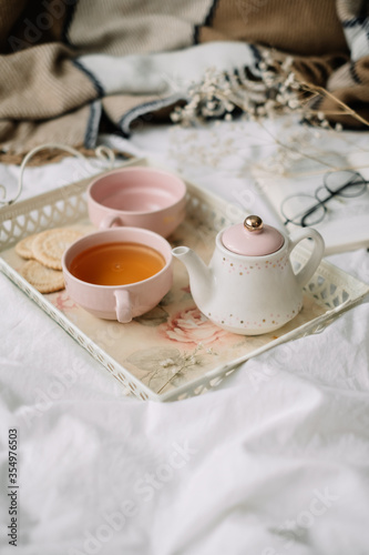 Kettle with tea and cups on a tray. Breakfast at home in bed, comfort and coziness.