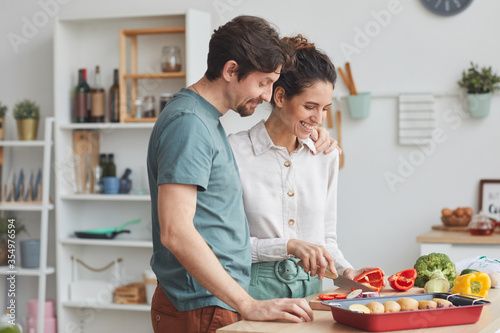 Young couple preparing food together in the kitchen they preparing dish from vegetables