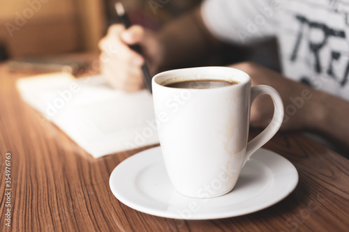 cup of coffee and man writing in background