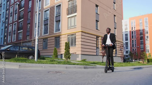 Smiling African-American returns from work to home on an electroscooter. Eco transport, care for the environment. photo