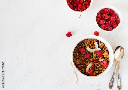 Granola with milk, coconut and berries - healthy energy breakfast or snack on a light background, top view.