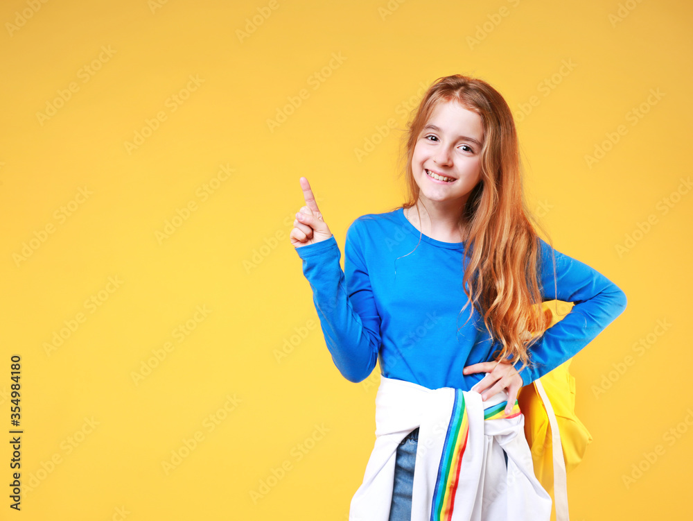 Schoolgirl point with finger empty space yellow background.Caucasian child pupil. Schoolgirl point with finger empty space yellow background.Caucasian child pupil.
