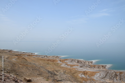 Dead Sea coast on the Jordanian side with salt deposits and bright blue water on a warm spring day  Dead Sea  Jordan
