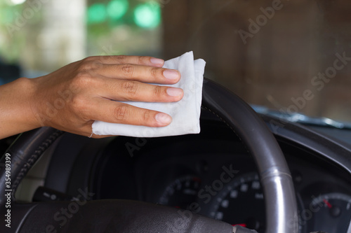 Cleaning Car steering whee with disinfecting wet wipes on surface to kill a coronavirus or touched area.