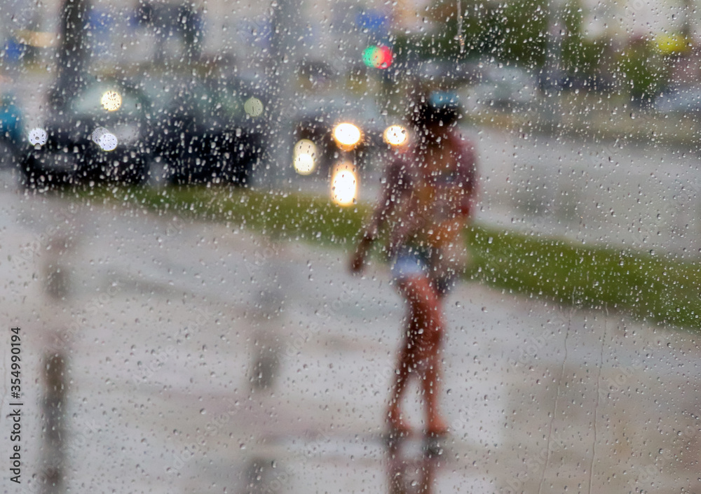 Fototapeta premium raindrops on window with person with umbrella