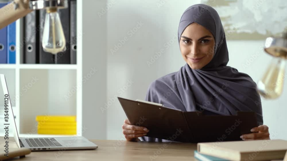 Muslim lady working in the office. Woman reading documents Muslim lady working in the office. Woman reading documents