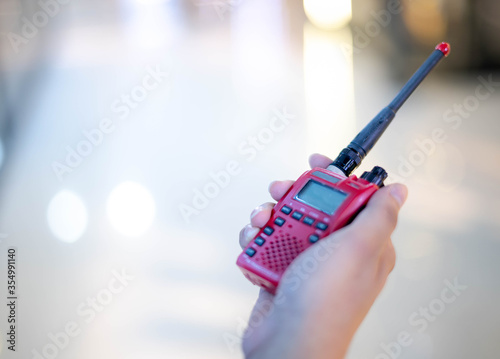 Φωτογραφία The male hand holding with a red Walkie Talkie or Portable radio transceiver for communication
