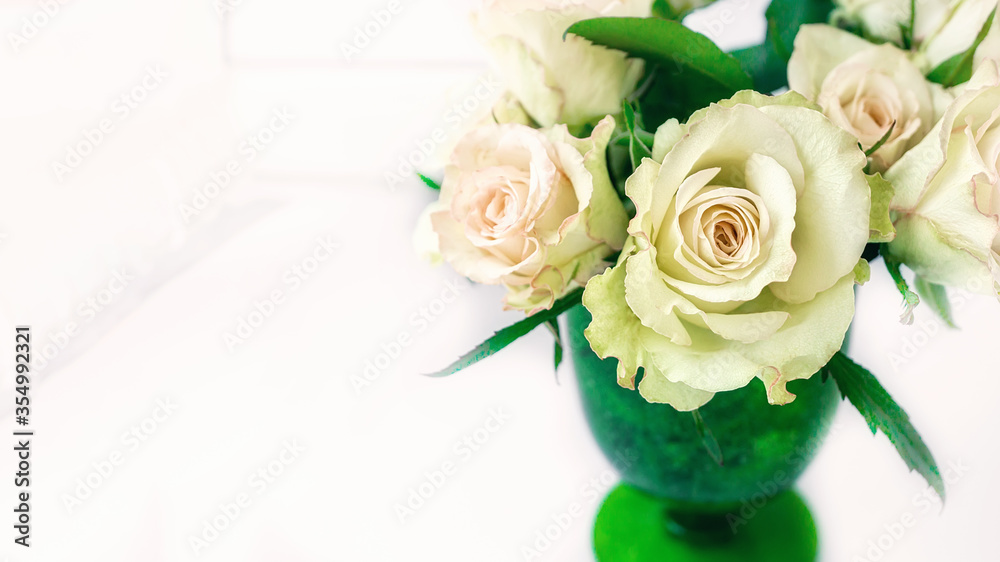 Romantic bouquet of delicate greenish roses in a green glass of thick glass on a light background. Close-up, copy space Romantic bouquet of delicate greenish roses in a green glass of thick glass on a light background. Close-up, copy space