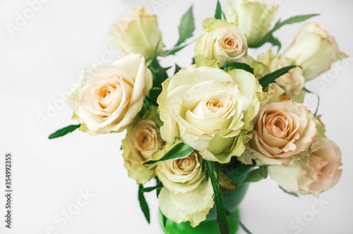 Romantic bouquet of delicate greenish roses on a light background. Background of cream and pink roses. Close-up  selective focus
