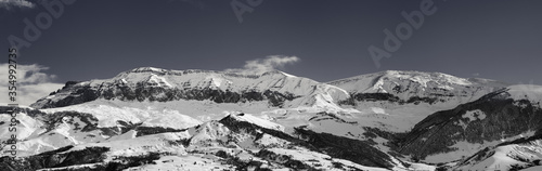 Panorama of high snowy mountains and sky with clouds at sun winter day