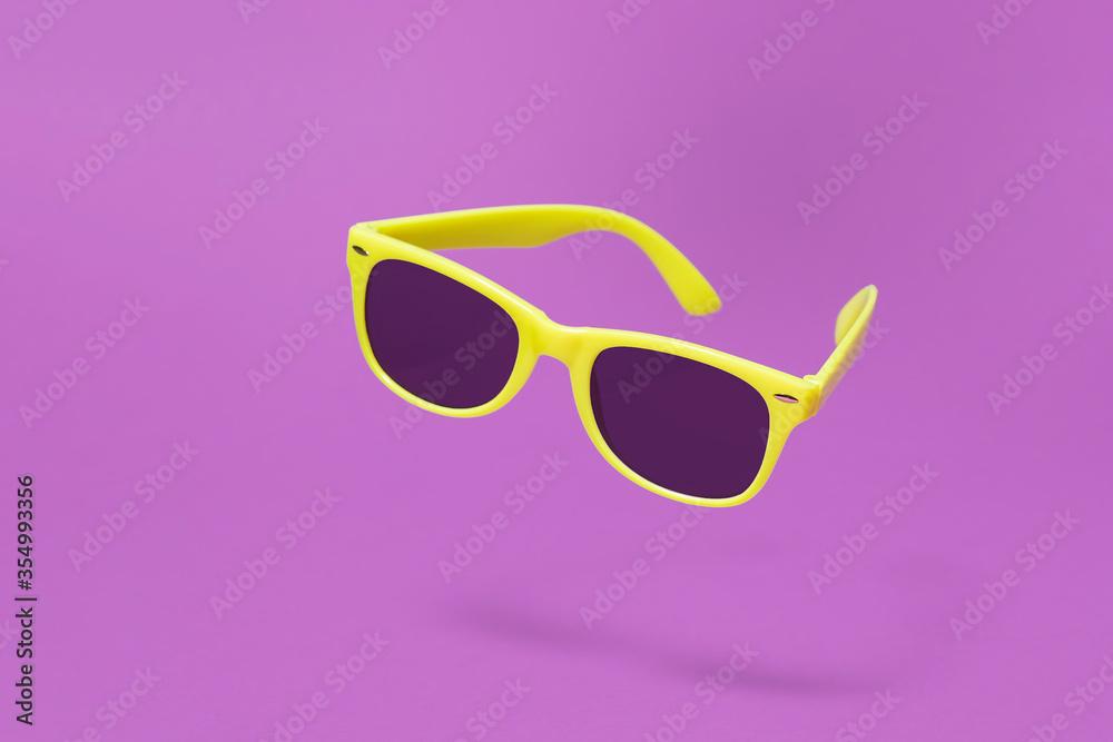 Yellow sunglasses floating above a purple background with a centre composition