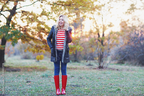 Tableau sur toile young beautiful blonde woman in red rubber boots posing in autumn park