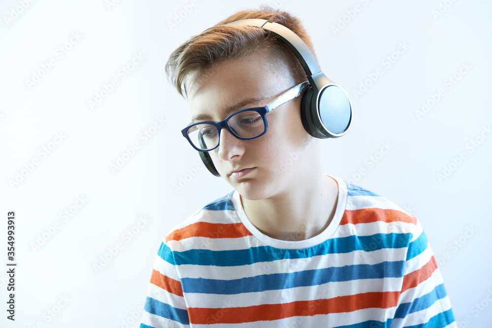 Sad teen boy listens to music on headphones