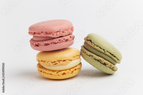 Pink, green and yellow macarons on white background