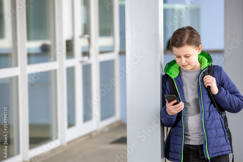 Truancy concept, young boy staying away from the school and playing games on the mobile, absence from school