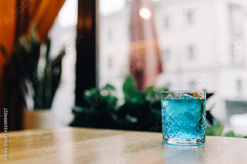Blue colored citrus alcohol cocktail on a table in a restaurant in a glass glass