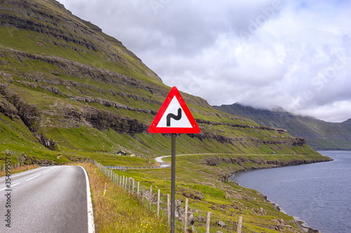 A typical situation in the Faroe Islands. A road winds beneath the mountains and above the fjords.