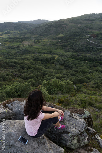 Woman sitting on rock observing landscape