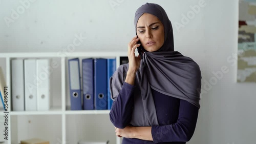 Muslim woman having an unpleasant conversation with her boss on the phone