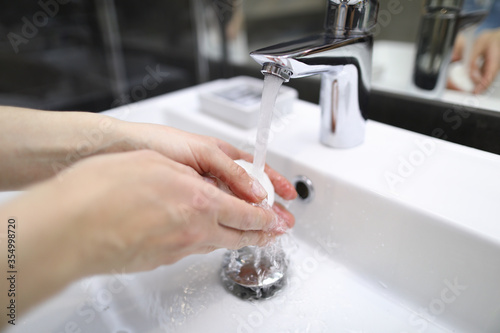Man thoroughly washes his hands with soap under tap