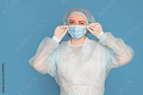 The doctor in a dressing gown, in medical gloves puts on a mask. Surgeon with clinical experience in healthcare, patient care