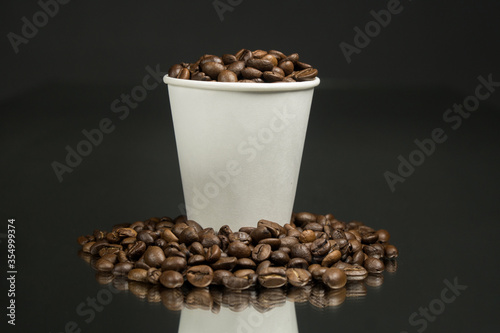 Paper cup of coffee and coffee beans on table