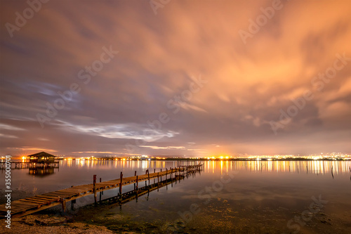 Beautiful night reflections in the sea from the port and moving clouds © EdVal