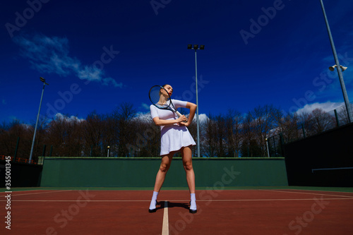 Sexy girl tennis player holding tennis racket on the court. Young woman is playing tennis. © Ivan Zelenin