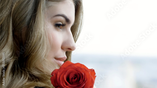 Beautiful girl in profile. Portrait of an attractive blonde young woman with red rose.