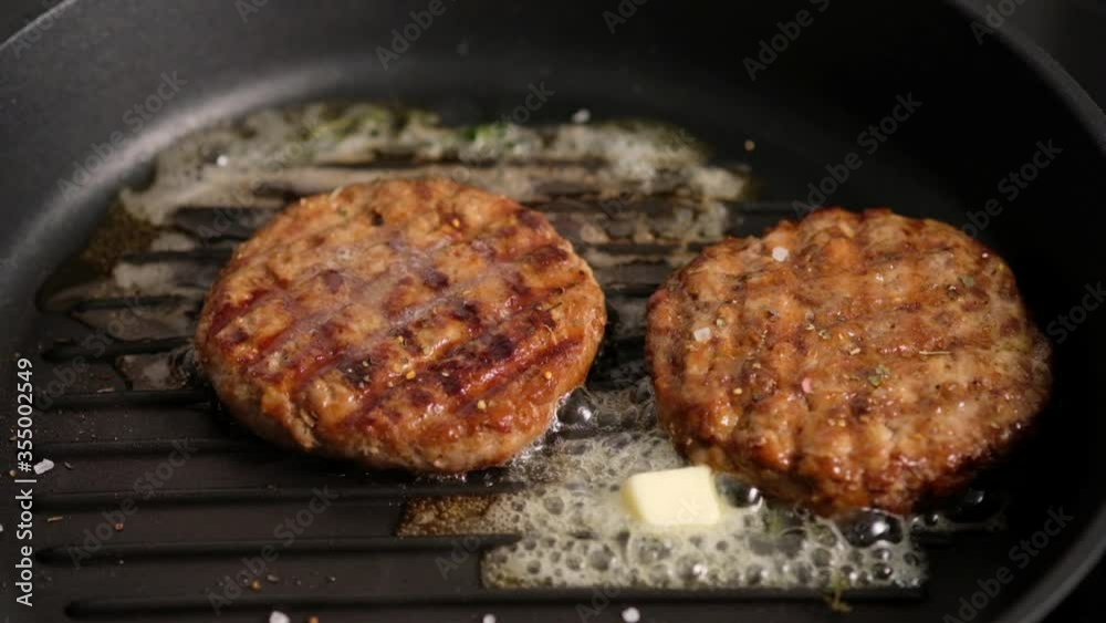 Grilled hamburgers on the grill. Burger cutlet is cooked in a grill pan, thyme, steam, smoke, fire. Butter is melted. Grill food. Slow motion. Grilled hamburgers on the grill. Burger cutlet is cooked in a grill pan, thyme, steam, smoke, fire. Butter is melted. Grill food. Slow motion.