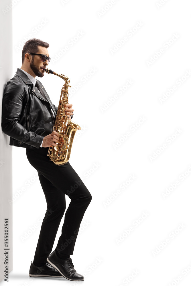 Naklejka premium Handsome young male musician in a leather jacket playing a saxophone