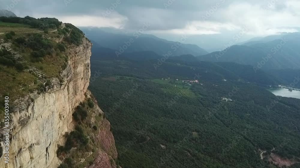 Aerial shot of rocky mountain cliff against cloudy sky, drone ascending forward over natural landscape - Tavertet, Spain Aerial shot of rocky mountain cliff against cloudy sky, drone ascending forward over natural landscape - Tavertet, Spain