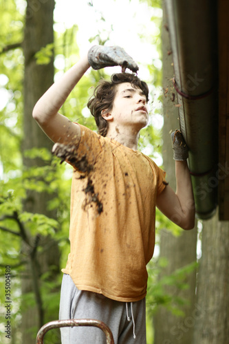 closeup photo of teenager boy cleaning roof from old leafs photo